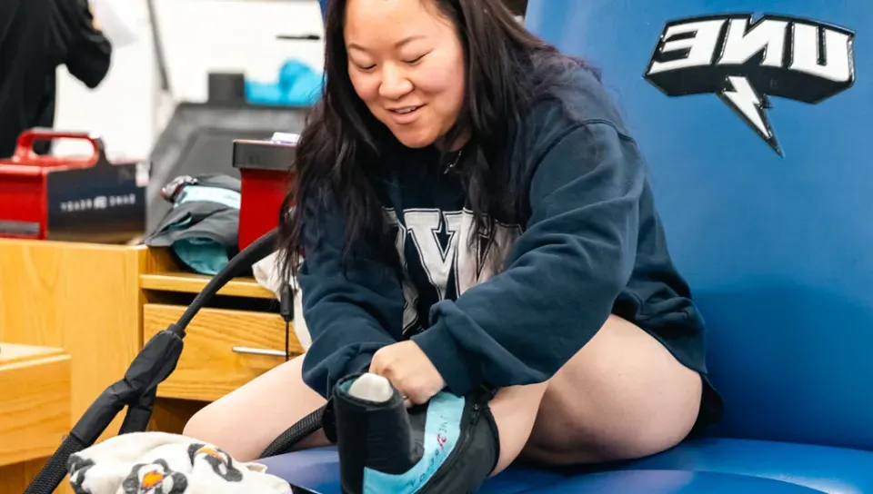 An athletic training student practices icing a foot injury on themself during class